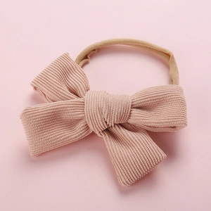 Détail du nœud en velours côtelé rose et du bandeau élastique en nylon pour bébé