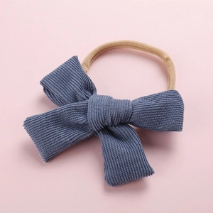 Texture détaillée du nœud en velours côtelé bleu sur bandeau bébé en nylon