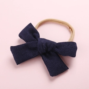 Détail du bandeau pour bébé en velours côtelé bleu marine avec grand nœud à la main