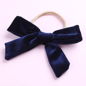 Détail d'un nœud en velours bleu marine sur un bandeau en nylon beige souple pour bébé