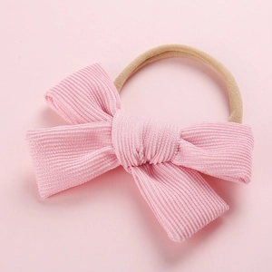 Gros plan d'un bandeau en velours rose avec un nœud et un élastique en nylon