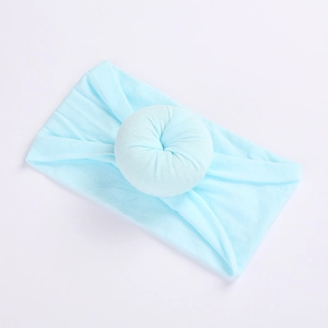 Soft baby nylon headband in light blue color with a decorative donut ball detail