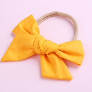 Gros plan détaillé d'un bandeau à nœud en coton jaune pour bébé sur fond rose pastel