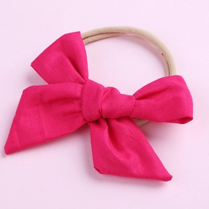 Détail d'un nœud en coton rose sur un bandeau en nylon beige extensible pour nourrissons