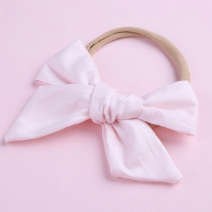 Détail macro du bandeau bébé en coton rose clair avec ruban en nylon très élastique
