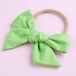 Détail d'un nœud en coton vert clair sur un bandeau pour bébé en nylon élastique