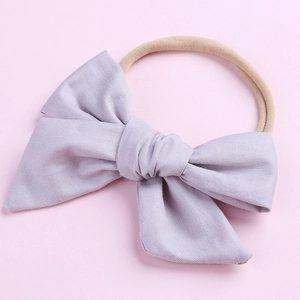 Détail d'un nœud en coton lilas doux sur bandeau en nylon élastique pour bébés