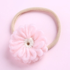 Vue détaillée d'une fleur crochetée à la main sur un bandeau en nylon doux pour bébé