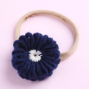 Détail d'une fleur tricotée bleu marine faite main sur un bandeau souple en nylon