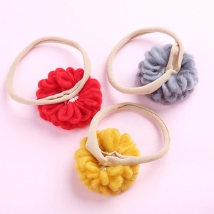 Détail des chouchous fleurs en laine faits main en rouge, jaune et gris sur nylon