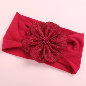 Macro shot of large red satin flower on soft nylon headband with beaded center detail