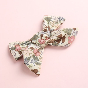 Katoenen strik haarspeld voor meisjes met roze bloemen op beige stoffen ondergrond