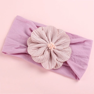 Detail of baby headband with a large silk flower and pearl stamens on pink nylon