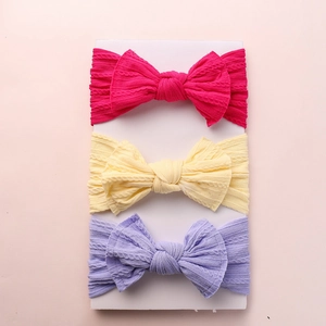 Three-pack knit nylon baby headbands with oversized bows in vibrant rose, yellow, and purple