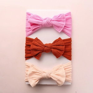 Three-piece set of soft ribbed knit baby headbands with decorative bows in neutral colors