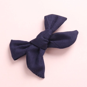 Détail d'un nœud papillon en lin bleu marine montrant la texture du tissu cousu main sur rose
