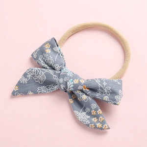 Floral print baby headband with grey cotton bow and soft elastic nylon band on pink background