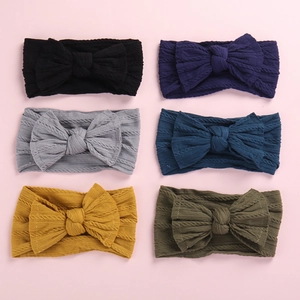 Close-up of knit nylon baby headbands with large bows in six assorted earthy colors
