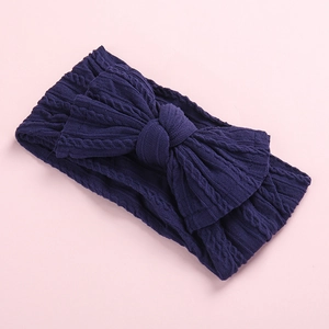 Detail of navy blue knitted cable knit headband featuring a textured bow accent