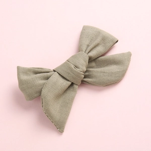 Détail d'une pince à cheveux en lin et coton vert olive avec une texture de tissu tissé