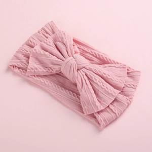 Close-up of pink cable-knit baby headband featuring a soft knit oversized bow texture