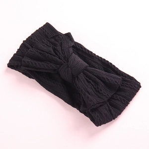 Detail of black cable knit headband featuring a large textured bow for children