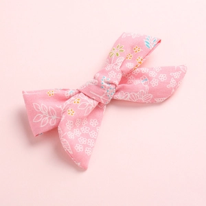 Detailed close-up of a pink floral fabric bow hair clip with delicate small flower patterns