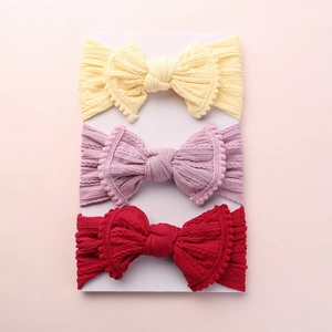 Détail de trois bandeaux pour bébé avec tissage jacquard, nœuds et bordures pompons