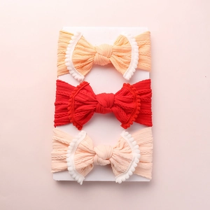 Détail de la texture tricotée de bandeaux bébé avec nœud et bordure à pompons