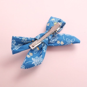 Detailed view of blue floral fabric bow hair clip with silver metal alligator clip back