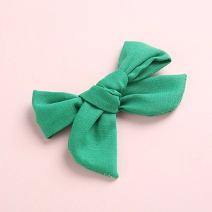 Détail d'une pince à cheveux avec nœud en coton vert montrant la texture du tissu