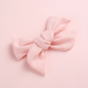 Détail d'une pince à cheveux en lin rose montrant la texture du tissu et le double nœud