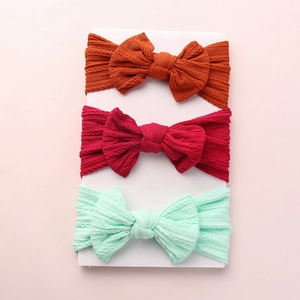 Three-pack soft jacquard nylon baby headbands with large bows in orange, rose, and mint