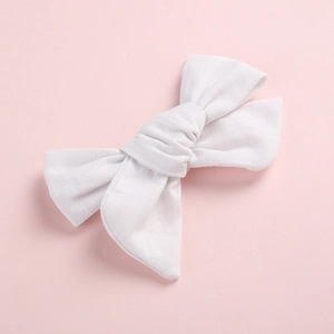 Détail d'une barrette à nœud blanc en tissu côtelé avec texture fine et design classique à deux couches