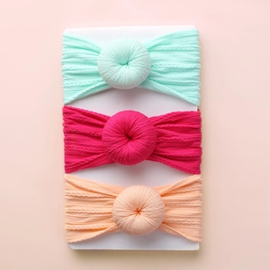 Detailed texture of baby donut headbands in mint, rose, and orange knitted fabric