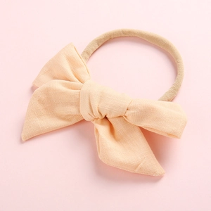 Détail d'un bandeau doux pour bébé avec nœud de couleur pêche et texture tissée