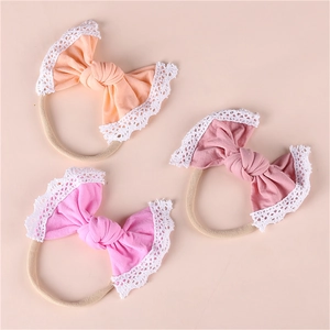 Detailed macro view of three soft nylon baby headbands with delicate white lace bow edges