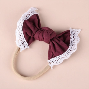 Detailed close-up of dark red nylon baby headband with delicate white lace bow edge