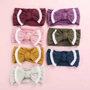 Bandeaux bébé en maille torsadée avec bordure pompons et nœud central en sept couleurs