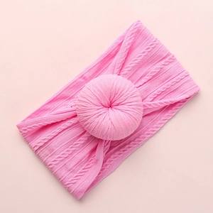 Close-up of pink baby headband showing soft cable knit texture and 3D donut knot