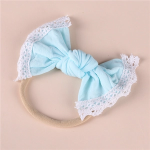 Detail of baby headband with light blue nylon bow and white lace trim on elastic band