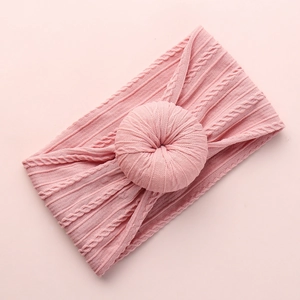 Close-up of pink knit baby headband with cable texture and 3D donut knot detail