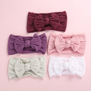 Detail view of five soft jacquard nylon baby headbands with large bows in various colors