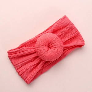 Detail of coral pink knit baby headband featuring a unique soft donut knot and cable pattern