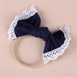 Detail of navy blue bow headband with white lace trim and elastic nylon band