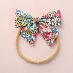 Weiches Nylon-Blumen-Stirnband für Babys mit buntem Blumenmuster auf rosa Hintergrund