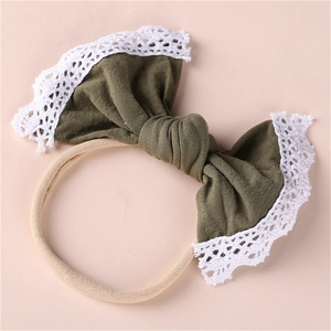 Detail of olive green bow baby headband with white lace edges on elastic nylon band