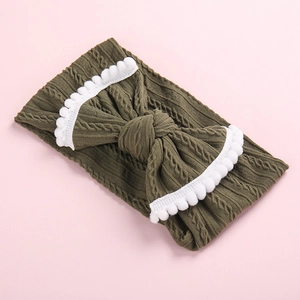Détail du bandeau bébé en tricot torsadé vert olive avec nœud et bordure pompons