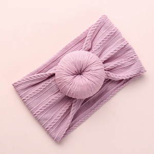 Close-up of soft pink cable knit baby headband featuring a circular donut knot detail