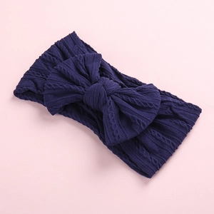 Detail of navy blue cable knit baby headband featuring a large matching bow